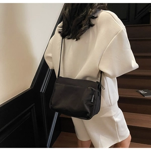Detail of black crossbody nylon bag featuring a branded zipper tag and multi-compartment design