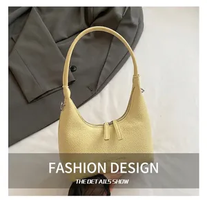 Dettaglio della borsa hobo con texture in pelle giallo crema su sfondo blazer grigio