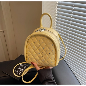 Detail of light yellow quilted backpack with sparkling rhinestones and silver zippers
