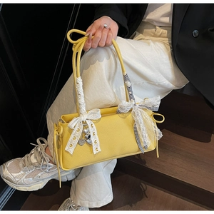 Detailed view of yellow lychee leather bag with lace ribbons and heart metal pendants