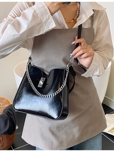 Minimalist black glossy bucket bag with silver chain strap and metal lock closure