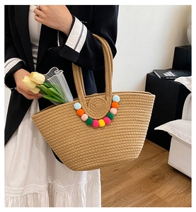 Détail du sac cabas en paille tissé avec pompons colorés et tulipes jaunes à l'intérieur