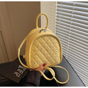 Detailed macro view of yellow quilted mini backpack with sparkling crystal embellishments