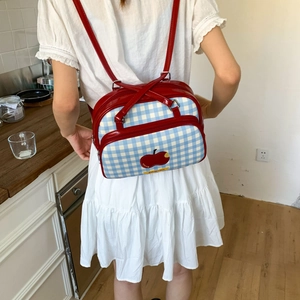 Detailed back view of a blue checkered backpack with red leather straps and apple print