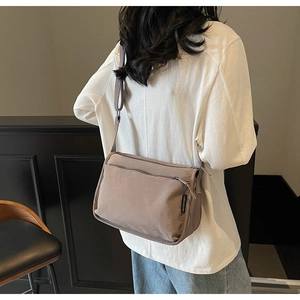 Detail showing the khaki canvas crossbody bag with adjustable strap on model