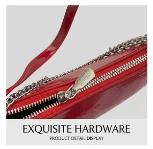 Close-up of silver metal zipper and chain details on red patent leather shoulder bag