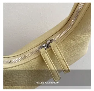Dettaglio ravvicinato della borsa beige con grana litchi e doppia cerniera in metallo