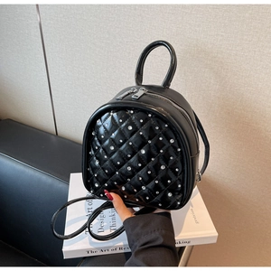 Detail of black diamond-quilted patent leather mini backpack with silver rhinestone accents