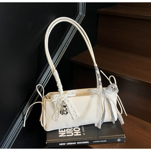 Detail of cream pebbled leather bag with lace bow and heart-shaped metal charms