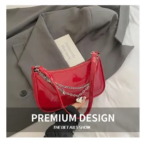 Detailed close-up of a red patent leather bag featuring silver chains and a heart pendant
