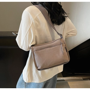 Crossbody taupe bag with wide strap shown from a back-side perspective on a model