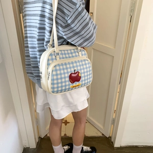 Detail shot of a blue and white checkered tote bag with an embroidered red apple patch