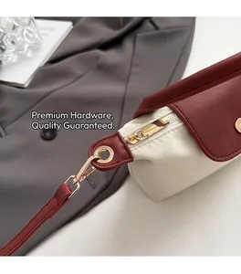 Detailed close-up of premium gold hardware and burgundy leather trim on a beige handbag