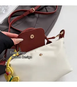 Detail of white nylon crossbody bag with brown leather flap and yellow duck charm