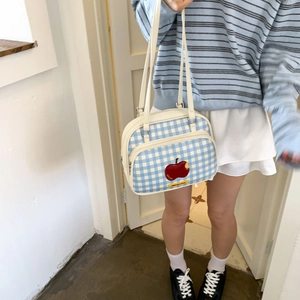 Detail of blue and white checkered tote bag with embroidered sweet apple badge and zipper