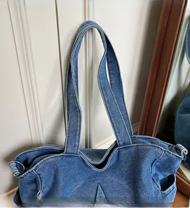 Detail of blue denim tote bag featuring long shoulder straps and metal ring hardware