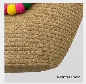 Vue détaillée d'un sac cabas en paille tissé à la main avec pompons colorés et texture spirale