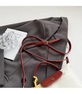 Detail view of the adjustable leather strap with gold metal buckle on a stylish square bag