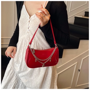 Detail of red patent leather shoulder bag with silver chains and heart charm