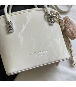 Detail of white marble texture bucket bag with silver hardware and a bear charm