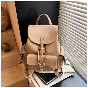 Detailed close-up of khaki litchi grain leather backpack with vintage metal buckles