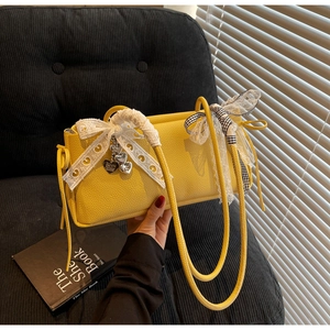 Close-up of yellow litchi pattern leather bag with lace bow and heart metal pendants