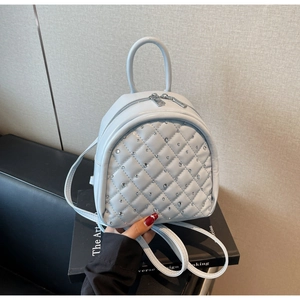 Close-up of light blue quilted mini backpack with rhinestone decor and metal zippers