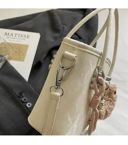 Close-up of beige bucket bag with silver hardware and cute plush doll charm detail