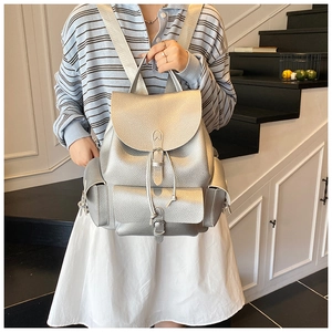 Detail of silver textured leather backpack with buckle straps and drawstring on a model