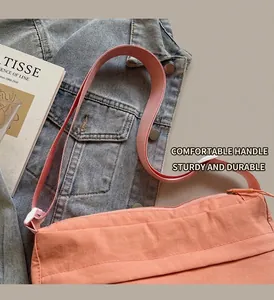 Detail of light coral nylon crossbody bag showing the durable texture and wide strap