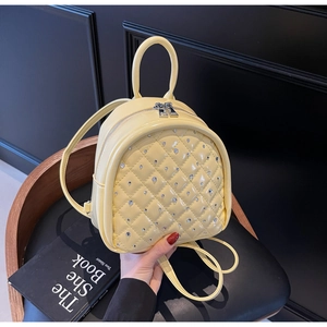 Detail of quilted leather mini backpack with shiny rhinestone studs and yellow finish