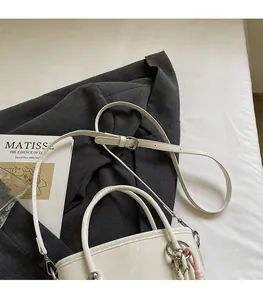 Detail of cream white leather bucket bag with adjustable strap and decorative charm