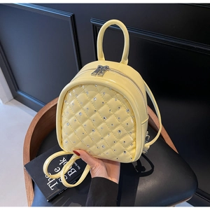 Close-up of yellow quilted mini backpack with sparkling rhinestones and patent finish
