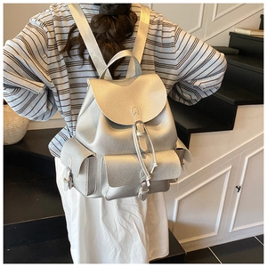 Detail shot of silver faux leather backpack showing pebbled texture and buckle pockets