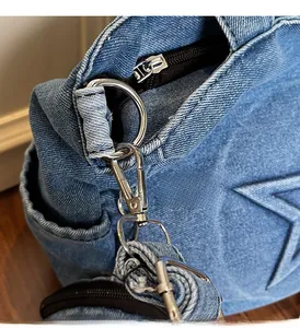 Close-up of the silver metal hook and black zipper on the blue denim tote bag