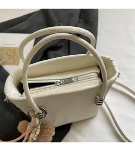 Detail view of cream white bucket bag with silver zipper and cute teddy bear charm