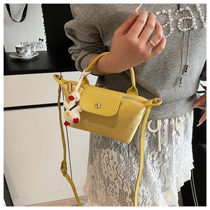 Close-up of yellow mini crossbody bag with cute white duck plush charm accessory