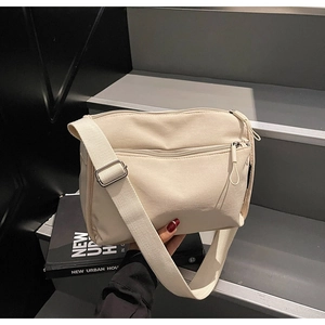 Detail view of cream canvas crossbody bag with adjustable strap and metal hardware details