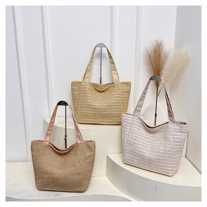 Three woven straw tote bags in beige and khaki displayed on a minimalist white stand