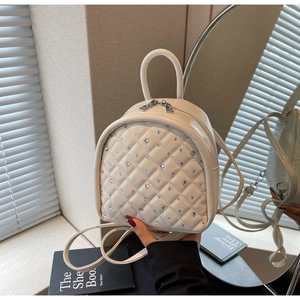 Close-up of beige quilted leather mini backpack featuring sparkling rhinestone accents