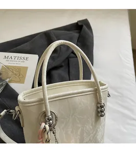 Detail of cream white bucket bag featuring beaded handle and decorative woven strap