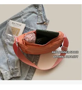 Detail showing the spacious interior of a coral pink nylon crescent bag with daily items