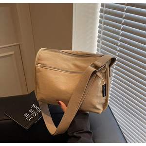 Detail of khaki canvas crossbody bag featuring multi-pocket design and wide shoulder strap