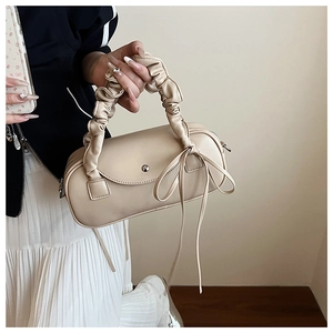 Detailansicht der cremefarbenen Zylindertasche mit gerafftem Griff und langer Schleife