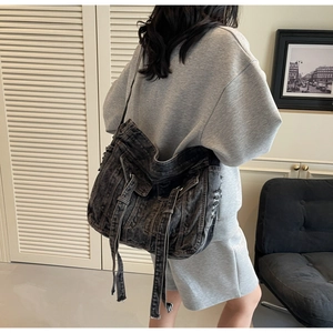 Detail of oversized black washed denim shoulder bag with multi-strap cargo style design