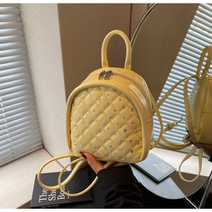 Close-up of yellow quilted mini backpack with rhinestone decor and glossy finish