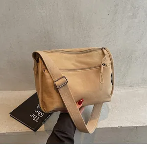 Close-up of khaki canvas crossbody bag with multi-layer zippers and wide fabric strap