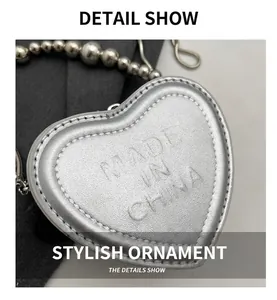 Close-up of silver heart-shaped mini bag with litchi texture and bead chain strap