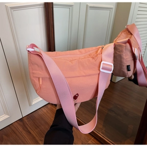 Detail of hot pink nylon crescent bag with adjustable wide strap and side zip pockets