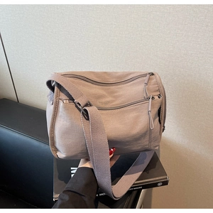 Close-up of taupe multi-pocket nylon crossbody bag with adjustable wide strap and zippers
